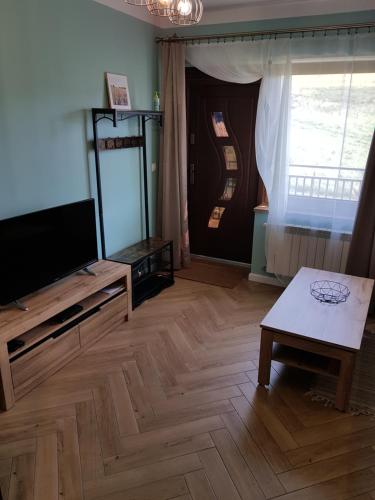 a living room with a flat screen tv and a table at Apartamenty Tylicki Poranek in Tylicz