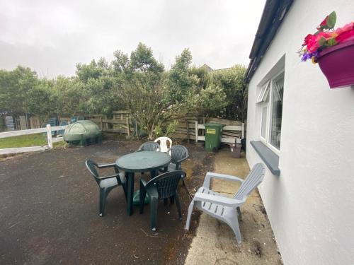 a patio with a table and chairs in a yard at Maisie's Seaside Cottage in Quilty