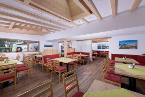 um restaurante com mesas e cadeiras de madeira e janelas em Familienhotel Central em Sankt Johann in Tirol