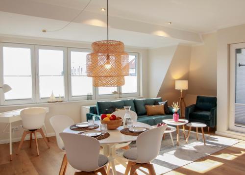 uma sala de estar com um sofá, uma mesa e cadeiras em Haus Vier Jahreszeiten em Wangerooge