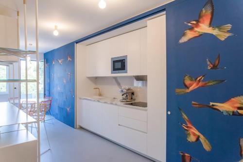 格拉多的住宿－Casa Agrado - Atemporary Art Apartments，厨房配有白色橱柜,墙上有鸟儿