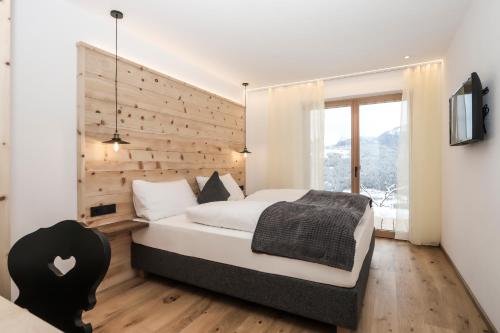 een slaapkamer met een groot bed en een houten muur bij HAUSERHOF CHALET in Villanders - moderne Wohnungen mit 2 Badezimmer und 2 Schlafzimmer in Villandro