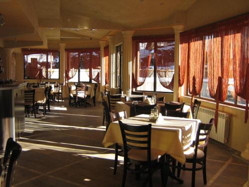 a dining room with tables and chairs and windows at Family Hotel Yola in Chepelare