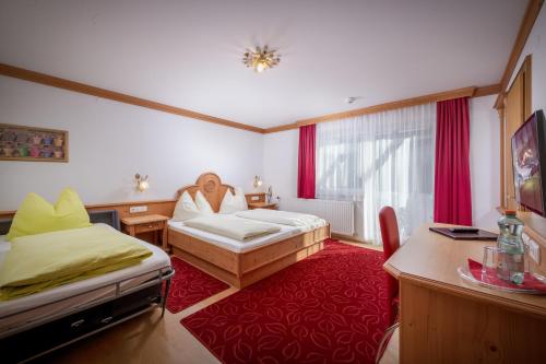 a hotel room with a bed and a desk and a room at Familienhotel Central in Sankt Johann in Tirol