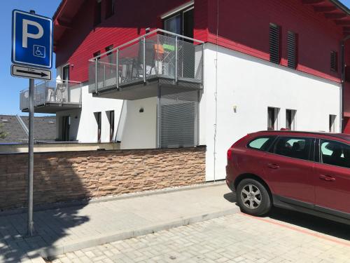 une voiture rouge garée devant un bâtiment dans l'établissement Apartmán Lipno, à Lipno nad Vltavou