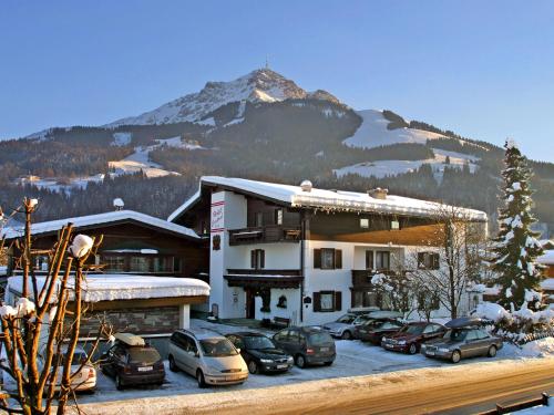 a hotel with cars parked in a parking lot with a mountain at Familienhotel Central in Sankt Johann in Tirol