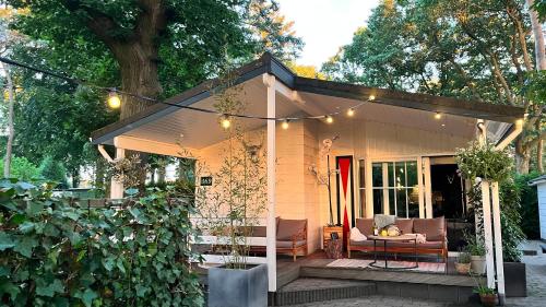 a small house with a porch with lights on it at Het Verwende Nest met privé hottub & Barrel sauna in Voorthuizen