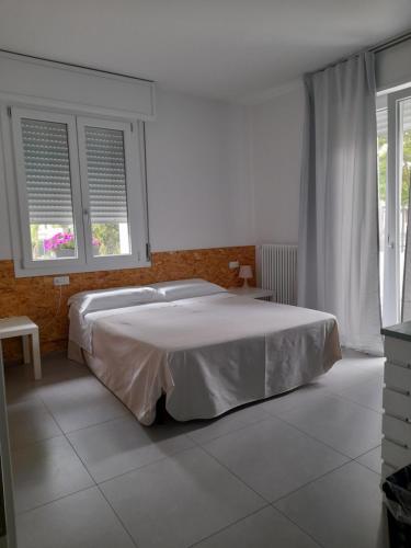 a white bedroom with a bed and two windows at R&B Manga Rosas in Lido di Dante