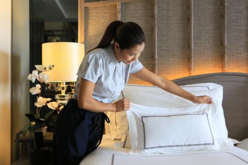 a woman laying on top of a bed in a hotel room at Riva Surya Bangkok - SHA Extra Plus in Bangkok
