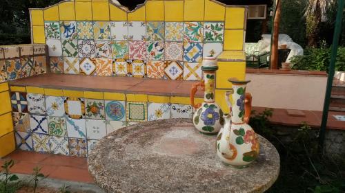 two vases sitting on a table in front of a bench at I Giardini di Palazzo Ducale in Pietramelara