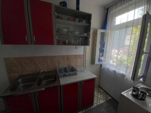 a kitchen with red cabinets and a sink and a window at Oriental Apartment in Plužine