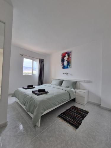 Un dormitorio blanco con una cama grande y una ventana en Torres del Sol 12th floor Teide and Atlantic view - Las Americas, en Playa de las Américas