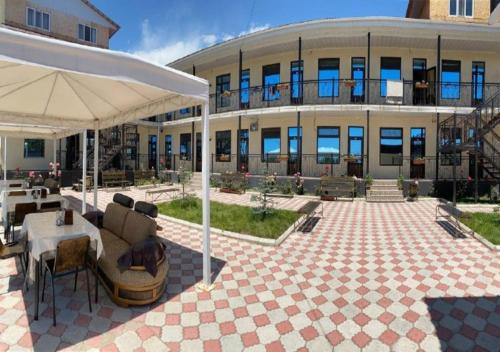 a building with a patio with a table and an umbrella at Aknur Deluxe hotel in Cholpon-Ata