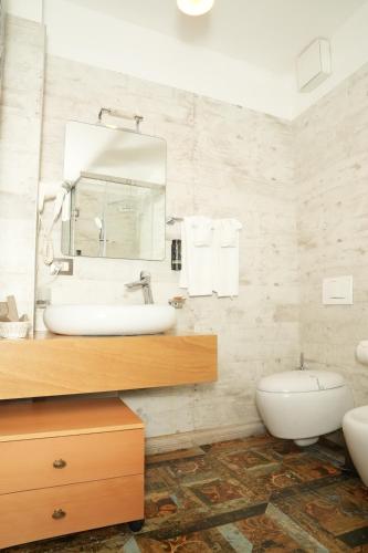 a bathroom with a sink and a toilet and a mirror at Hotel Boutique Vila 8 in Durrës