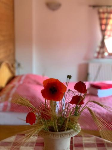 a vase filled with red flowers on a table at Penzion Selský dvůr Braňany in Braňany