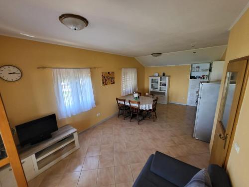 ein Wohnzimmer mit einem Tisch und eine Küche mit einer Uhr in der Unterkunft Apartment Prvic Sepurine in Prvić Šepurine