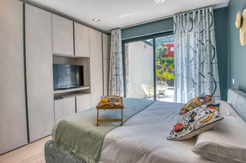 a bedroom with a bed with a tv and a window at Deluxe VILLA GRAZIELLA 200 M FROM THE BEACH in Èze