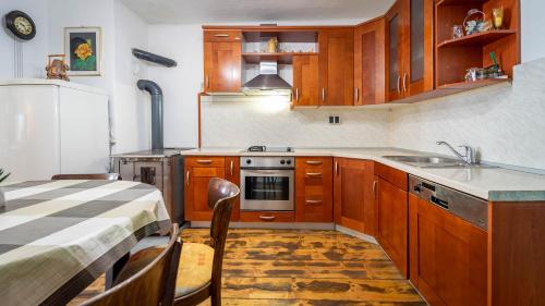 a kitchen with wooden cabinets and a sink and a table at Kuća za odmor ''Julka'' in Plešce