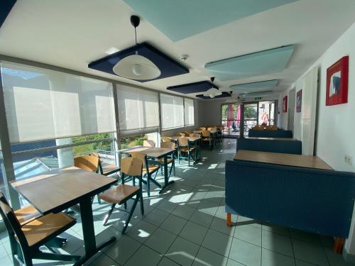 una sala da pranzo con tavoli, sedie e finestre di Village de vacances Fleurs et Neige ad Aussois