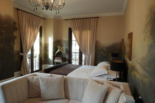 a bedroom with a bed and a couch and windows at Hotel Boutique Vila 8 in Durrës