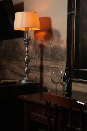 a table with two wine glasses and a lamp at Hotel Boutique Vila 8 in Durrës