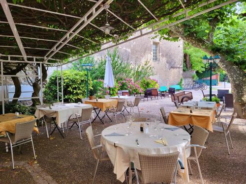 a group of tables and chairs under a pergola at Logis Hotel la Ferme in Avignon