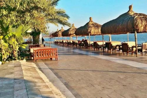 una fila de mesas y sillas con sombrillas en la playa en Egedeki Eviniz 2, en Koycegiz