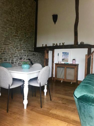 une salle à manger avec une table et des chaises blanches dans l'établissement La Paix, Gîte bucolique en Normandie, à Condé-sur-Noireau