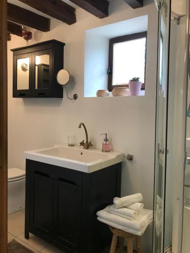 une salle de bain avec un lavabo et des toilettes et une fenêtre dans l'établissement La Paix, Gîte bucolique en Normandie, à Condé-sur-Noireau