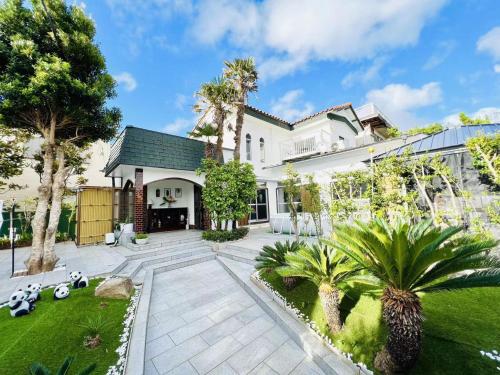 a large white house with a courtyard with palm trees at 海の眺め/プール付き/炭火BBQ(雨でも可能)/まるまる貸切別荘/最大13名/名勝千畳敷・三段壁近く in Shirahama