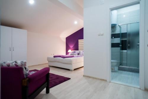 1 dormitorio con cama y pared de acento púrpura en Purple rooms, en Mostar