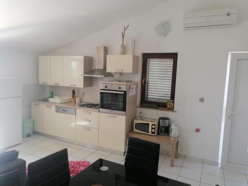 a kitchen with white cabinets and a microwave at Apartman ViL in Sveti Vid-Miholjice