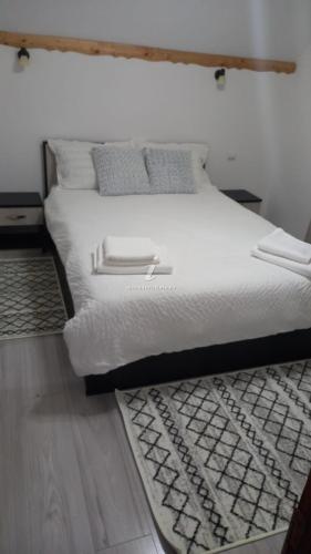 un letto con lenzuola e cuscini bianchi in una camera da letto di Dor de munte a Măgura