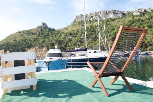 una silla de madera sentada en la cubierta de un barco en House boat R al Poetto 2 pax piu' 1, en Poetto