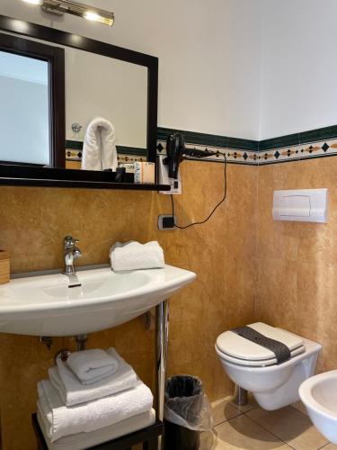 a bathroom with a sink and a toilet and a mirror at Cassisi Hotel in Milazzo