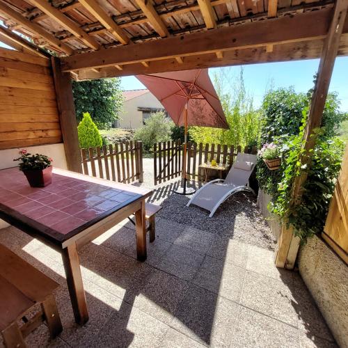 a patio with a table and an umbrella at Le Chant de l'Alyte in Lens-Lestang