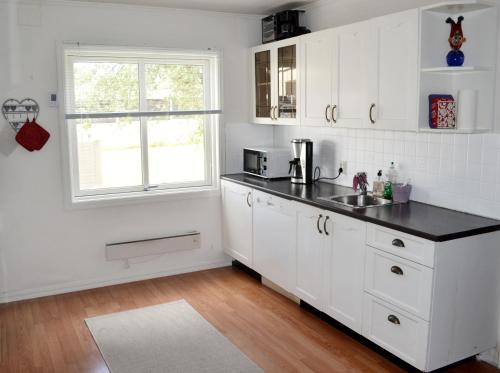 una cucina con armadi bianchi e piano di lavoro nero di Endless Summer a Tønsberg