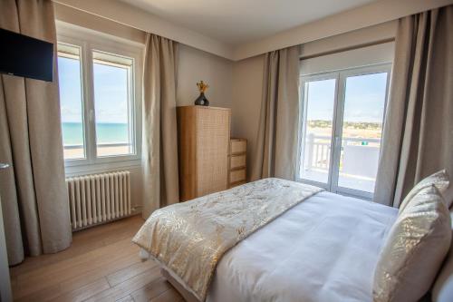 a bedroom with a bed with a view of the ocean at Hôtel des Isles in Barneville-Carteret
