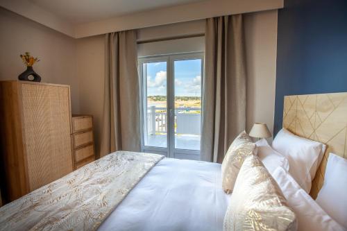 a bedroom with a bed with a large window at Hôtel des Isles in Barneville-Carteret