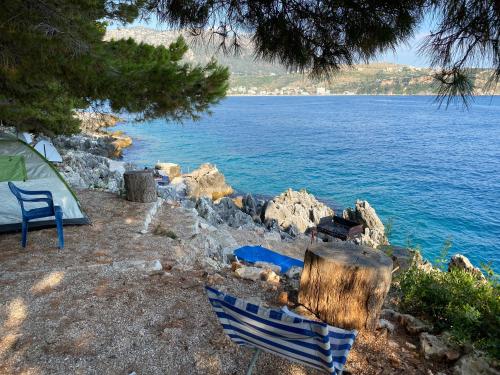 a tent and two chairs next to a body of water at Pine Side Camp in Himare