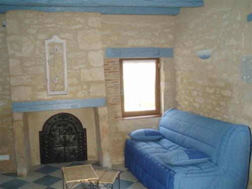 a living room with a blue couch and a fireplace at AUX PETITES PIERRES DE PEYROUSSELLE in Montignac