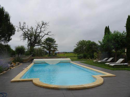 a swimming pool in a garden with chairs around it at AUX PETITES PIERRES DE PEYROUSSELLE in Montignac