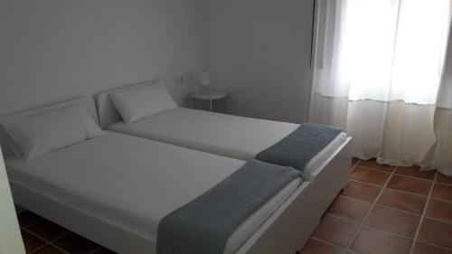 Una cama blanca en una habitación con ventana. en Moderna casa de pueblo en el casco viejo de Jávea, en Jávea
