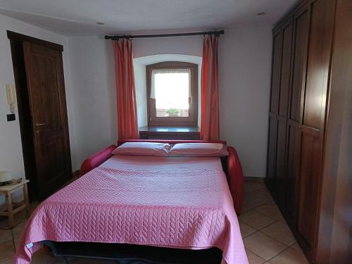 a bedroom with a bed with a pink blanket and a window at Lo PONTON in Introd
