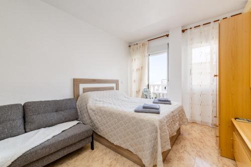 - une chambre avec un lit, un canapé et une fenêtre dans l'établissement Studio Caballero de Rodas, à Torrevieja