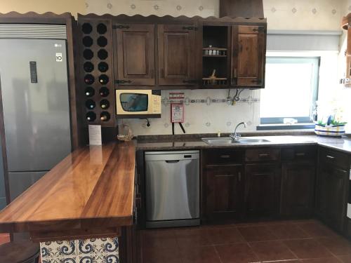 a kitchen with wooden cabinets and a stainless steel dishwasher at Ribeirinho da Serra in Penela