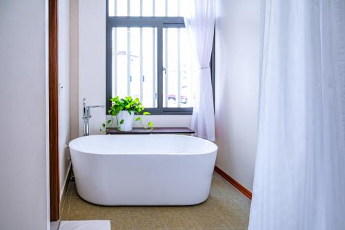 a white bath tub in a bathroom with a window at The King Hotel - Condotel Thai Nguyen in Thái Nguyên