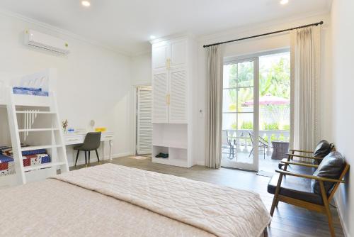 a white bedroom with a bed and a table and chairs at La villa de CoCo Bến Tre in Ben Tre