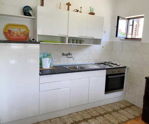 a kitchen with white cabinets and a sink at Olive apartments in Grebaštica