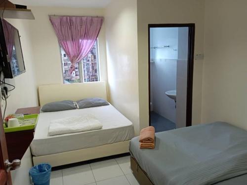 a bedroom with two beds and a bathroom with a window at CH Budget Hotel in Cameron Highlands